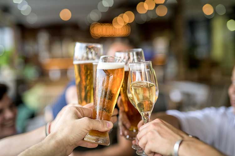 Cropped image of friends toasting drinks in celebration.