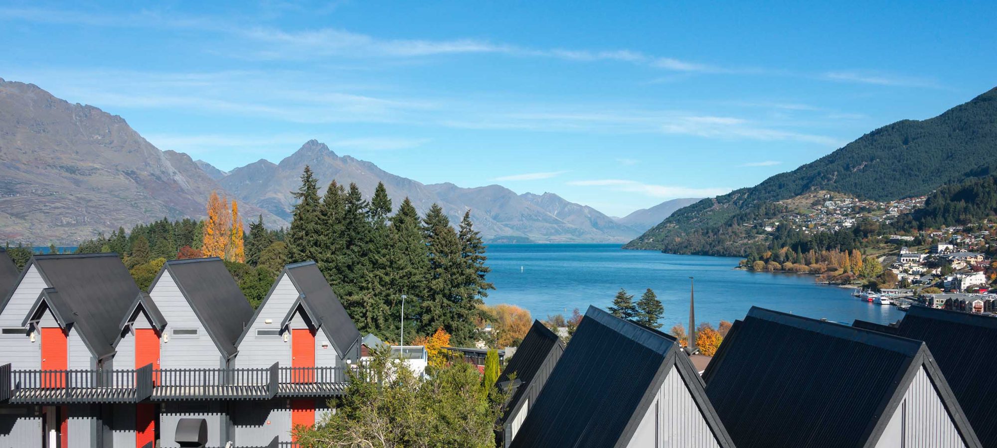 Heartland-Hotel-Queenstown-Rooms-Exterior-Lake-Mountain-Views-Blue-Sky-Banner