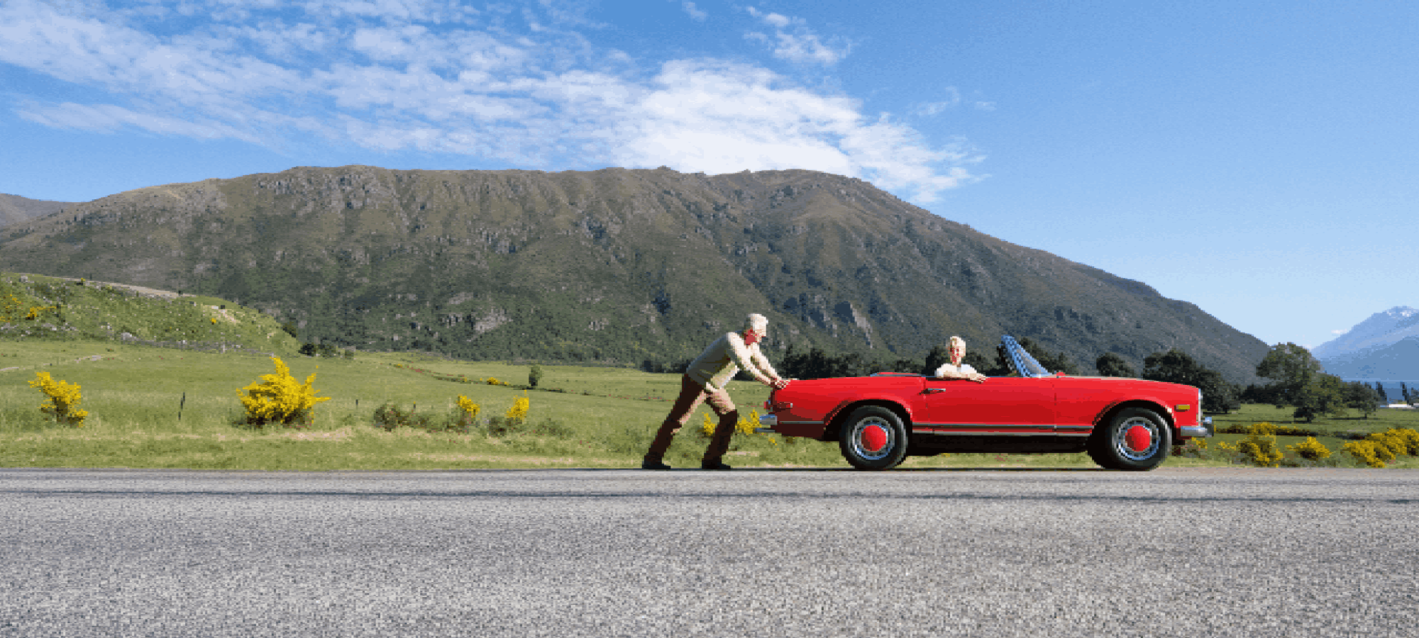 Senior pushing red convertible